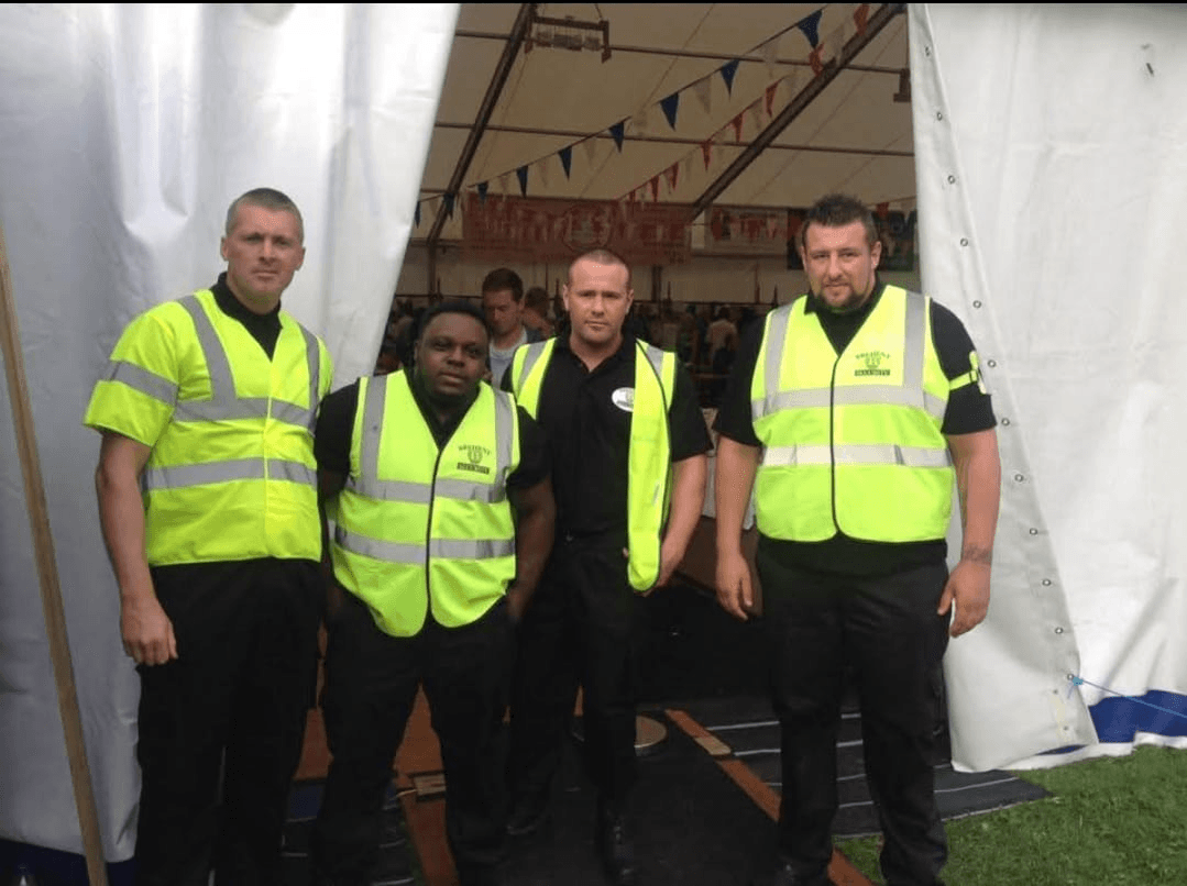 A friendly but professional door supervisor checking tickets at the entrance to a corporate event.